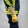 Seitliche Ansicht eines Feuerwehrmanns in Schutzausrüstung, der Penkert Elk Defender 3.0 Feuerwehrhandschuhe mit langem Stulpen trägt, hellbraunes Design mit orangen Akzenten.