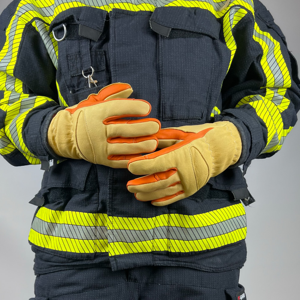 euerwehrmann trägt die Penkert Elk Defender 3.0 Kurzvariante Handschuhe in einem gelben Feuerwehranzug, zeigt die Handschuhe in Einsatzposition von vorne.