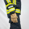 Ein Feuerwehrmann steht mit ausgestrecktem rechten Arm und trägt Penkert FireDevil 911 X-treme lange Handschuhe, wobei die reflektierenden Streifen und das Penkert-Logo auf dem Arm zu sehen sind.