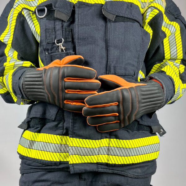 Feuerwehrmann in Schutzausrüstung trägt Penkert New Dimension 3.0 Feuerwehrhandschuhe mit kurzem Stulpen, schwarzem und orangefarbenem Design, bereit für den Einsatz.