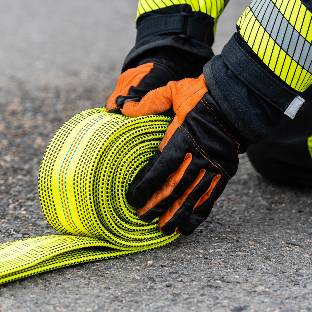 Eine Nahaufnahme von Penkert-Handschuhen, die einen Feuerwehrschlauch während eines Einsatzes handhaben.