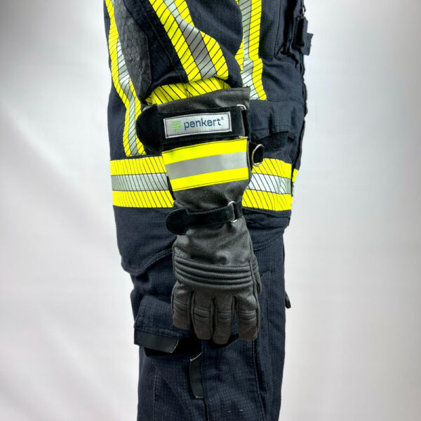 Seitenansicht eines Feuerwehrmannes in Feuerwehrschutzkleidung mit reflektierenden Streifen, die einen langen Schutzhandschuh mit Klettverschlüssen und Penkert-Logo trägt.