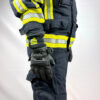 Seitenansicht einer Person in Feuerwehrschutzkleidung mit reflektierenden Streifen, die einen kurzen Schutzhandschuh trägt.