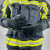 Feuerwehrmann in vollständiger Schutzausrüstung, trägt schwarze Penkert FireGrip 3.0 Feuerwehrhandschuhe mit langem Stulpen, die über der Schutzjacke getragen werden. Die reflektierenden Streifen der Jacke sind sichtbar und betonen die professionelle Einsatzkleidung.