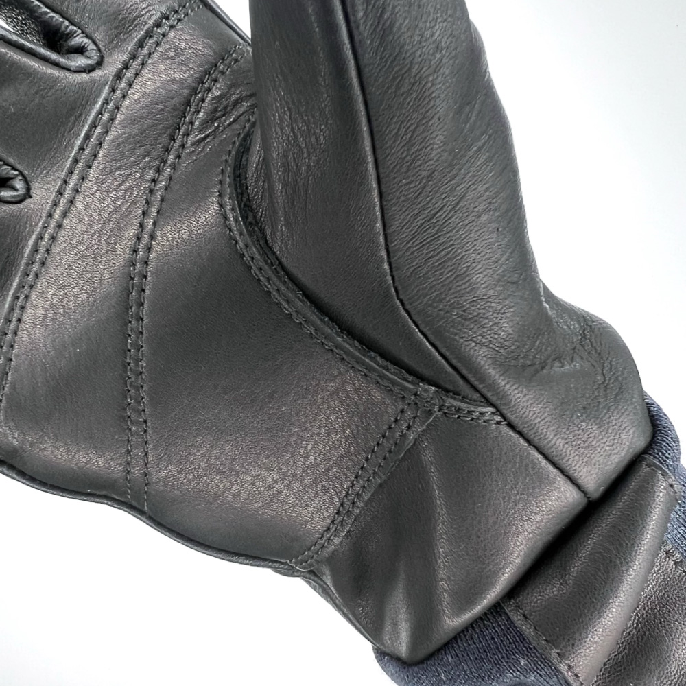 Nahaufnahme eines schwarzen Lederhandschuhs mit Fokus auf die Nähte in der Innenhand.